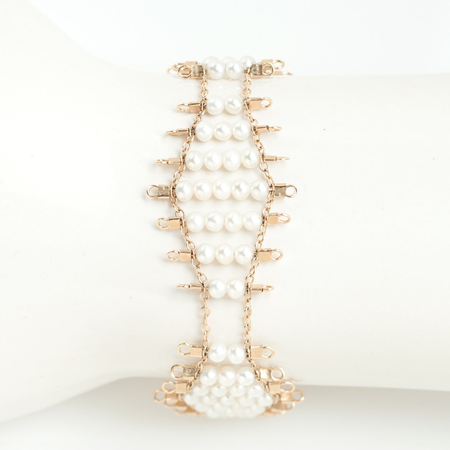 Kellan bracelet, featuring undulating rows of lustrous, white pearls, suspended on rows of 14k gold-fill wire and chain, and finished with a lobster clasp. Approximately 7 inches in length.