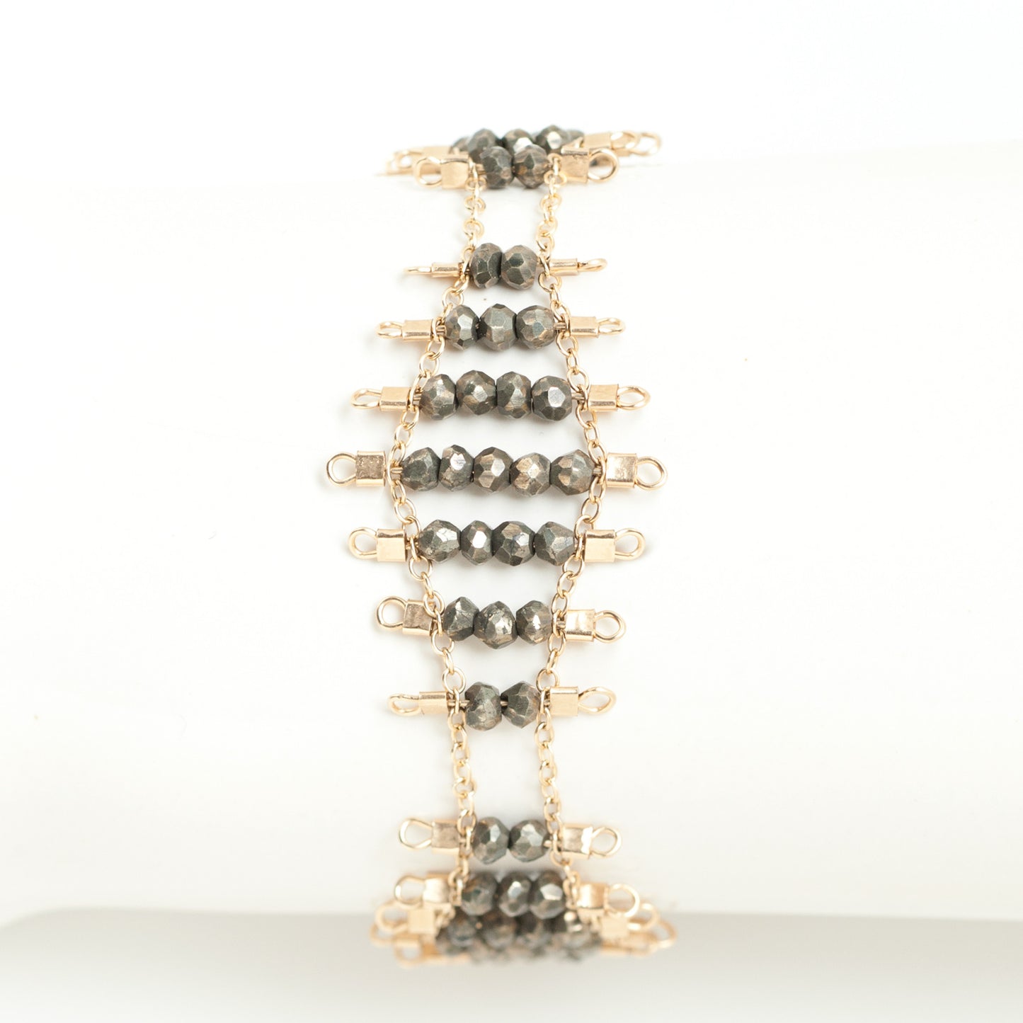 Kellan bracelet, featuring undulating rows of metallic, faceted pyrite beads, suspended on rows of 14k gold-fill wire and chain, and finished with a lobster clasp.  Approximately 7 inches in length.