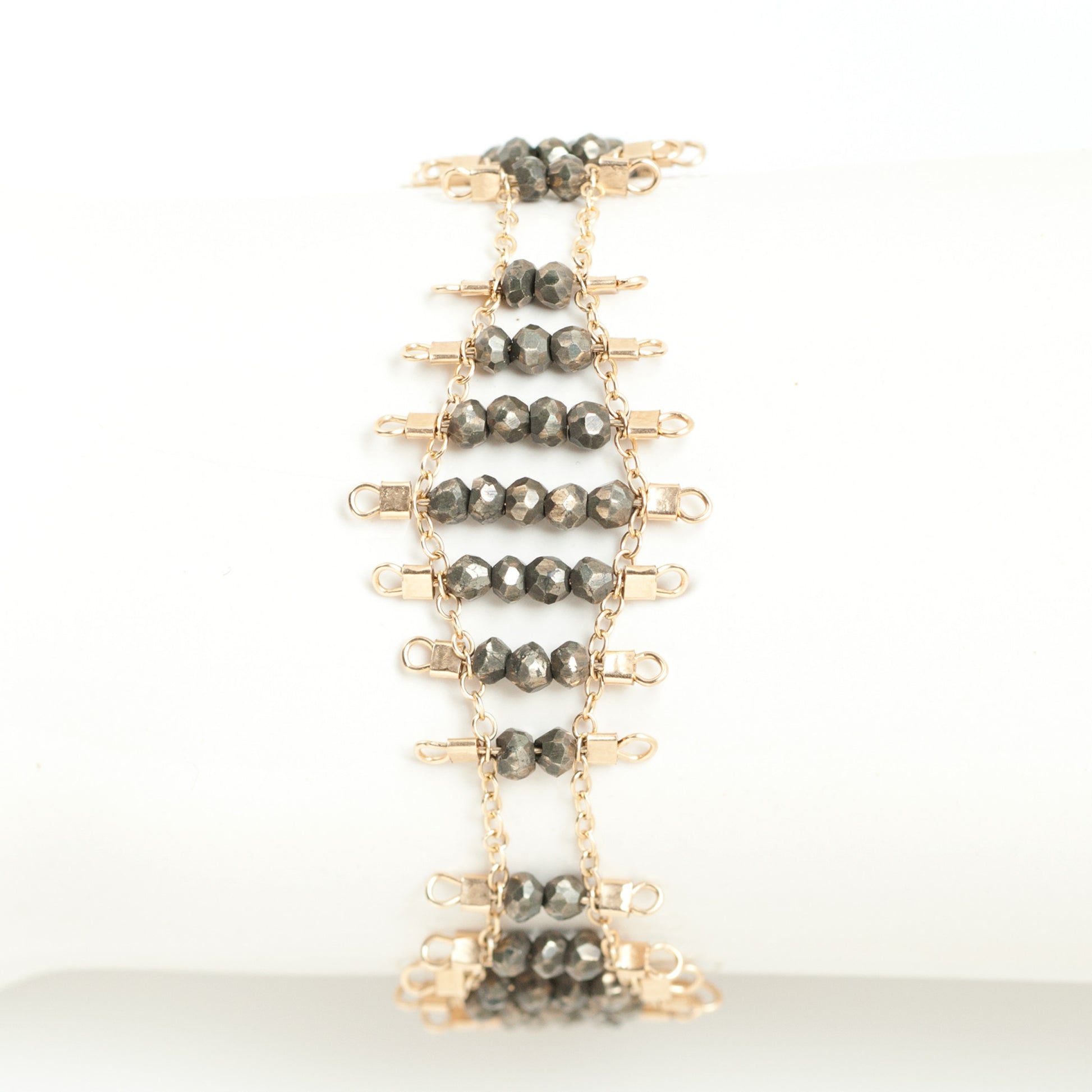 Kellan bracelet, featuring undulating rows of metallic, faceted pyrite beads, suspended on rows of 14k gold-fill wire and chain, and finished with a lobster clasp.  Approximately 7 inches in length.