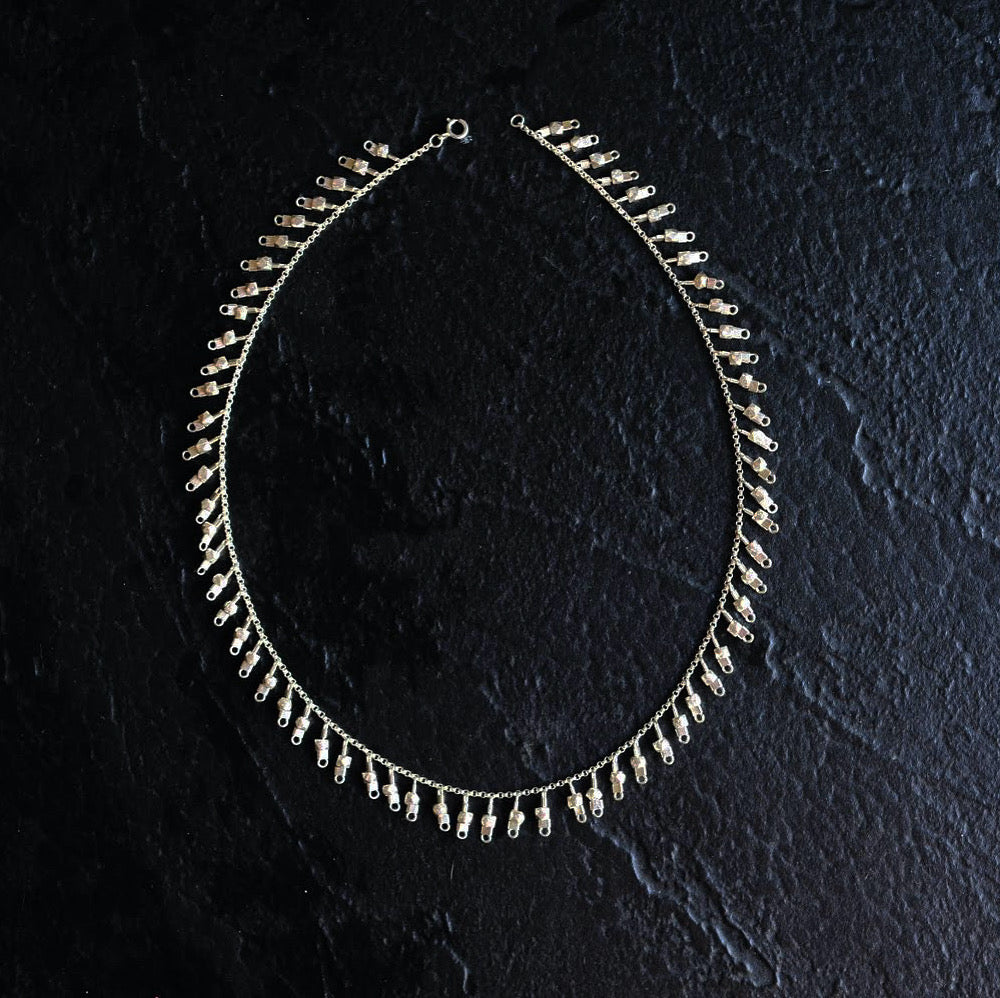 A sterling silver fringe-style necklace of silver faceted beads dangling off a silver chain all the way around.