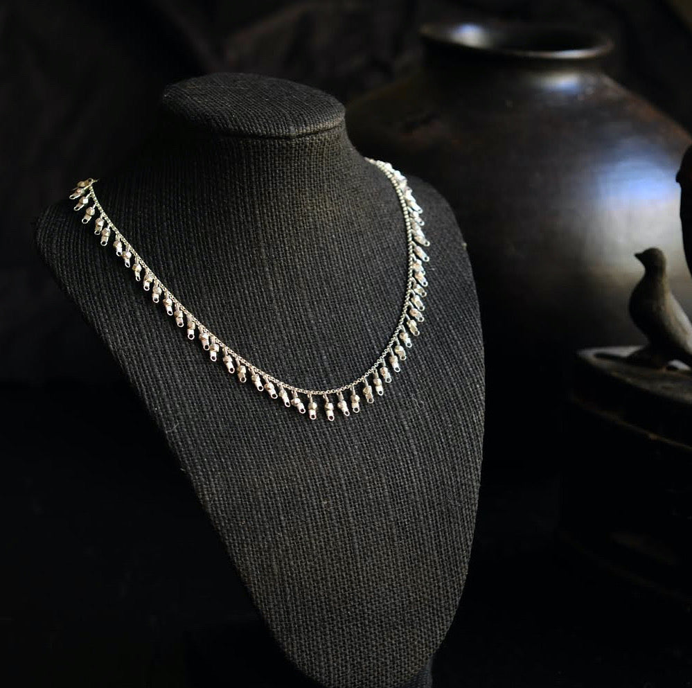 A sterling silver fringe-style necklace of silver faceted beads dangling off a silver chain all the way around.