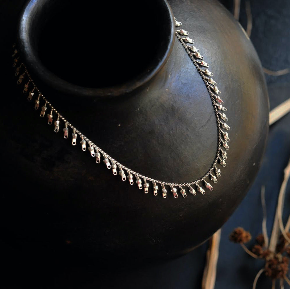 A sterling silver fringe-style necklace of silver faceted beads dangling off a silver chain all the way around.