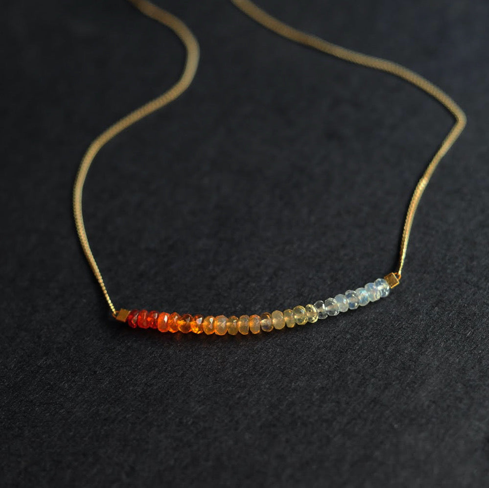 A thin, gold chain necklace strung with 2 inches of Mexican fire opal in milky to orange ombre tones.