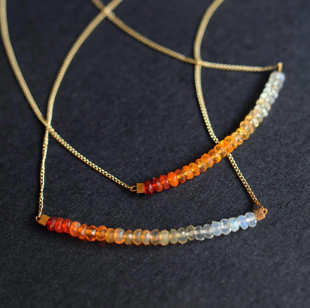 A thin, gold chain necklace strung with 2 inches of Mexican fire opal in milky to orange ombre tones..