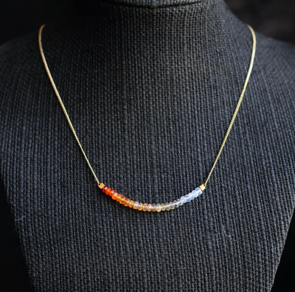 A thin, gold chain necklace strung with 2 inches of Mexican fire opal in milky to orange ombre tones.